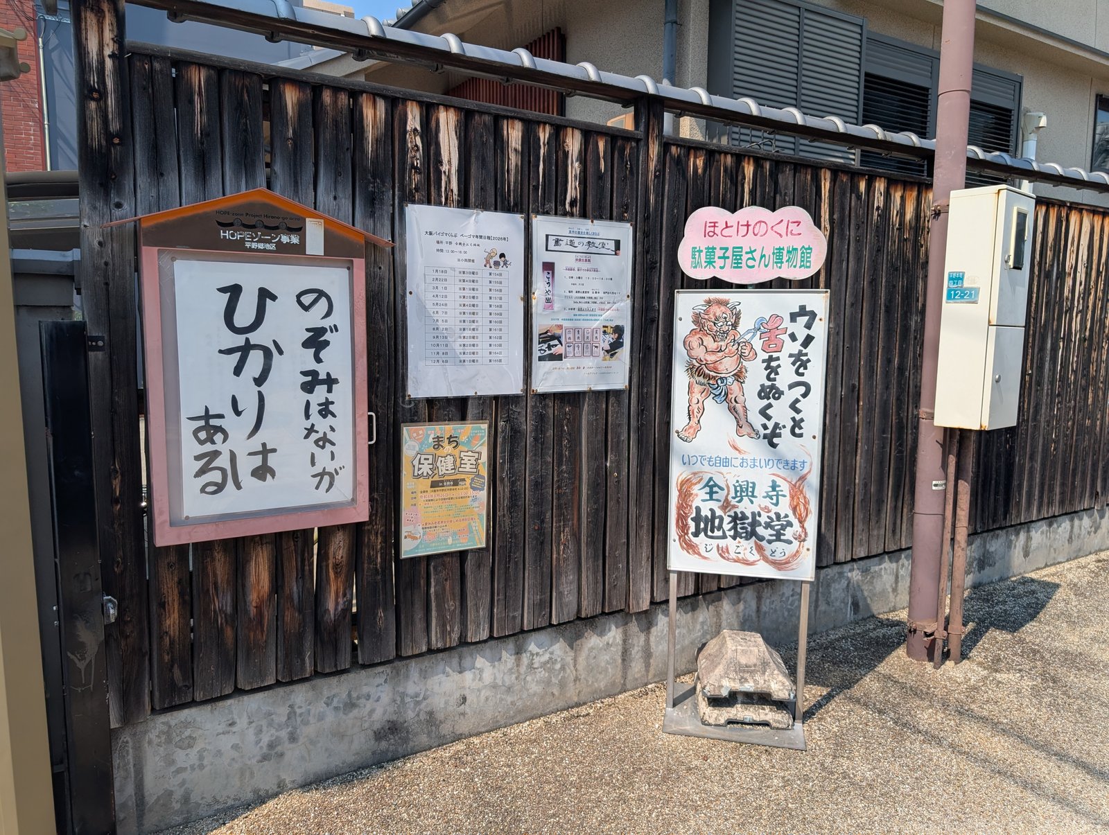 板塀の掲示「のぞみはないが ひかりはある」